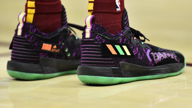View of black, purple, and green Adidas Dame shoes.